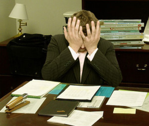 "Frustrated man at a desk (cropped)" by LaurMG. - Cropped from "File:Frustrated man at a desk.jpg".. Licensed under CC BY-SA 3.0 via Wikimedia Commons.